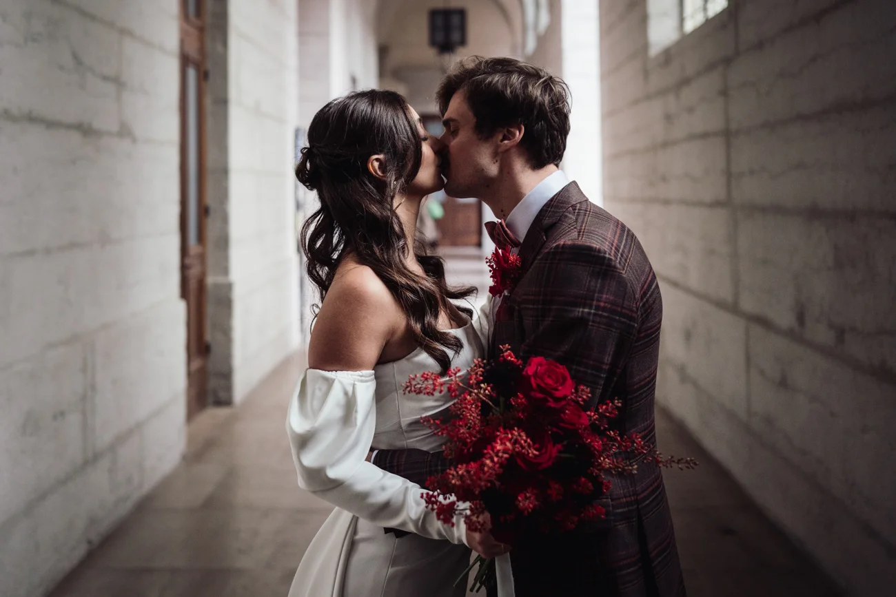 Un couple romantique se baigne dans l'ambiance intime d'un couloir vintage, l'homme tenant un bouquet de roses rouges.