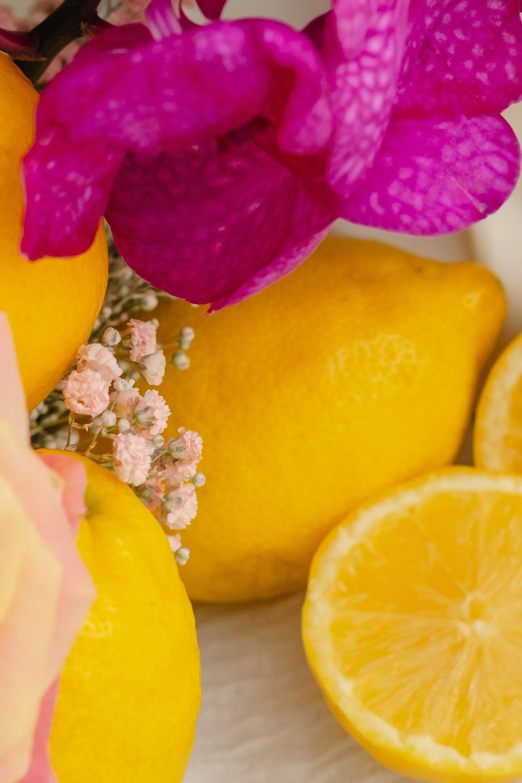 Composition colorée de citrons jaunes et d'orchidées fuchsia pour une décoration de table de mariage estivale.