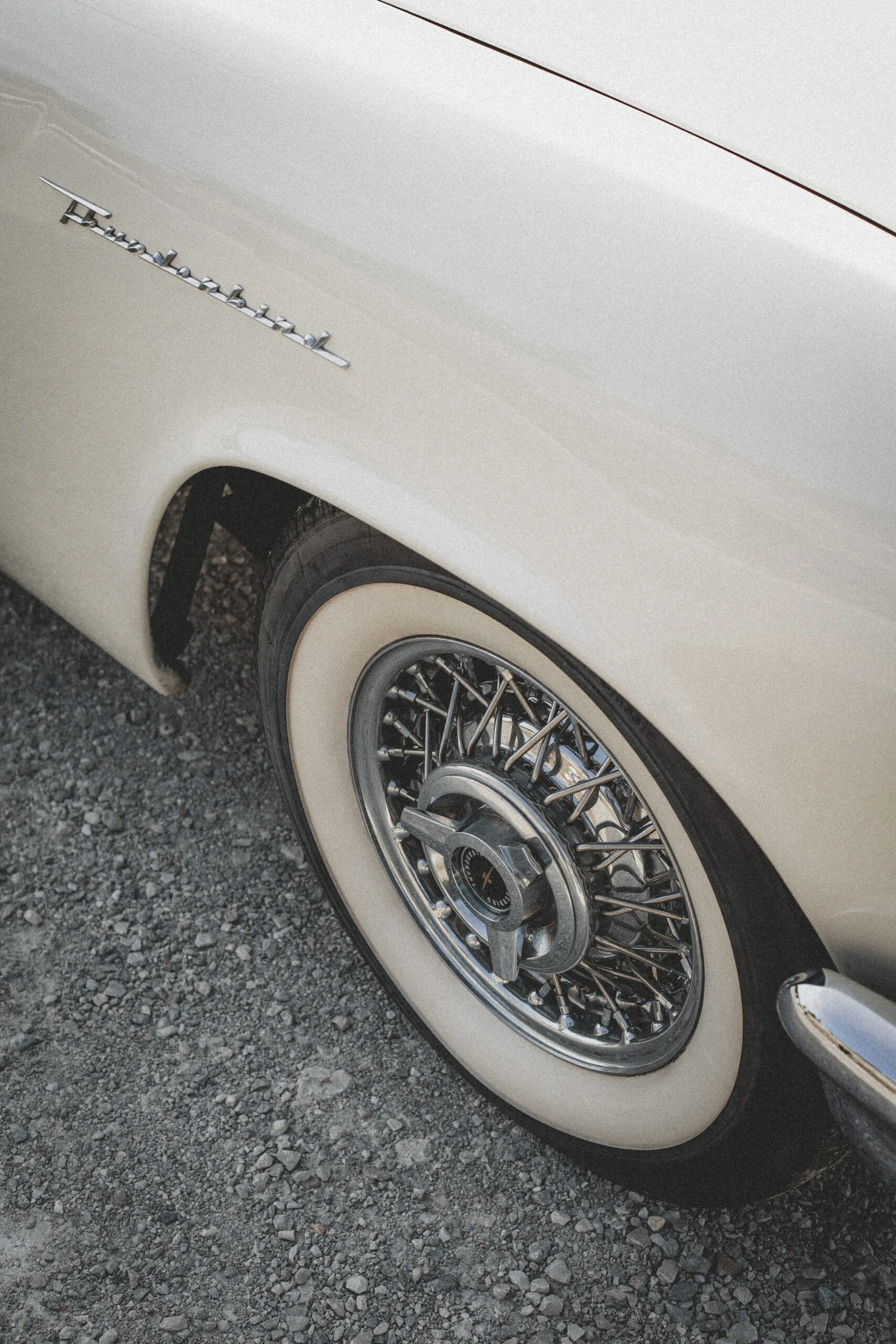 Gros plan sur la roue à rayons et le pneu blanc d'une voiture ancienne blanc cassé, style rétro et élégant.