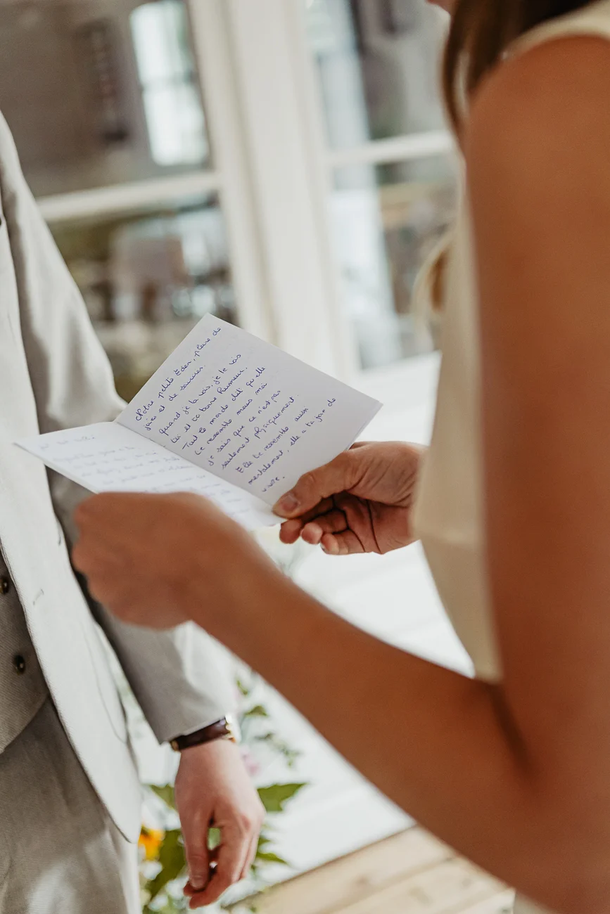 Une mariée lit ses vœux manuscrits à son futur époux lors d'une cérémonie intime et lumineuse.