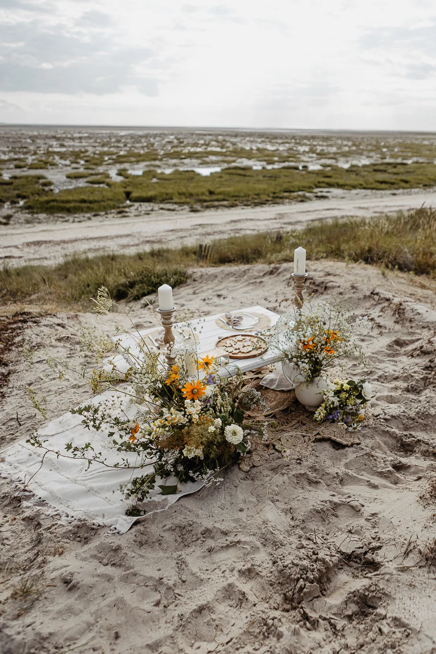 Pique-nique romantique et bohème sur le sable avec fleurs sauvages et bougies, face aux paysages de Saint-Valery-sur-Somme.