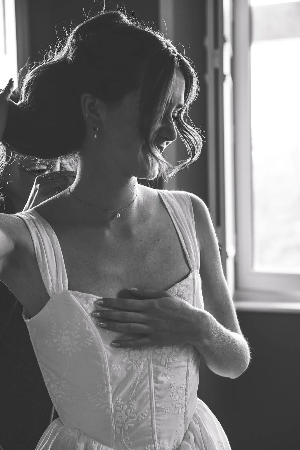 Portrait en noir et blanc d'une mariée en robe blanche se préparant dans une ambiance romantique et lumineuse.