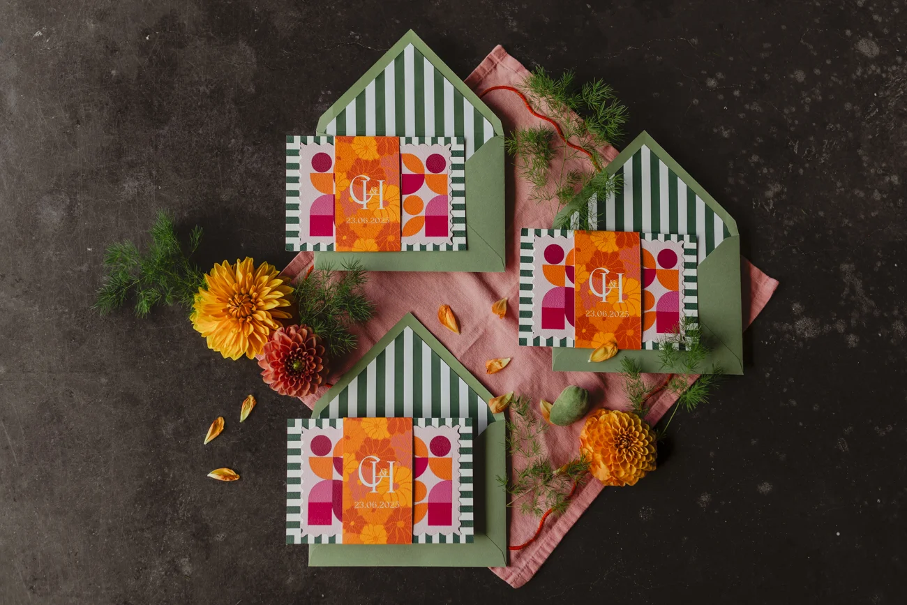Faire-part de mariage rétro aux motifs géométriques orange et rose, avec enveloppes vertes rayées et fleurs d'automne.