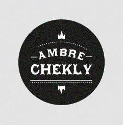 Logo circulaire noir avec le nom Ambre Chekly écrit en blanc dans un style typographique vintage et élégant.