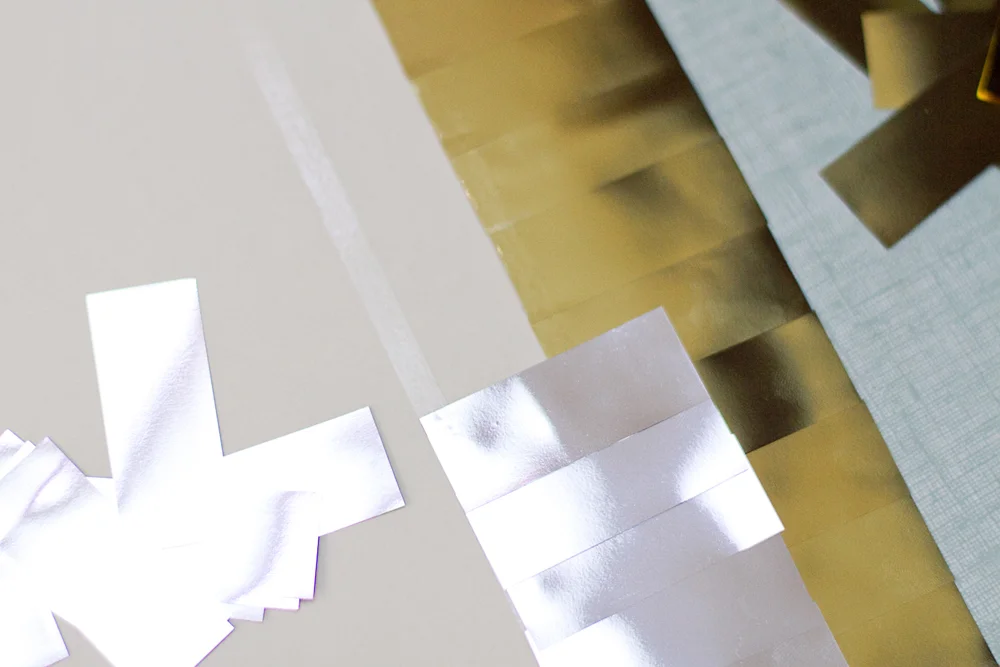 Bandes de papier brillant argentées et dorées disposées sur un fond neutre pour un atelier DIY.