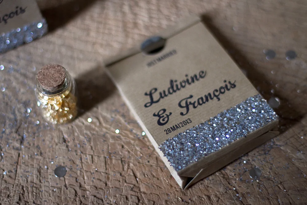 Sachet en papier kraft personnalisé pour mariage avec paillettes argentées et petite fiole de sequins dorés.