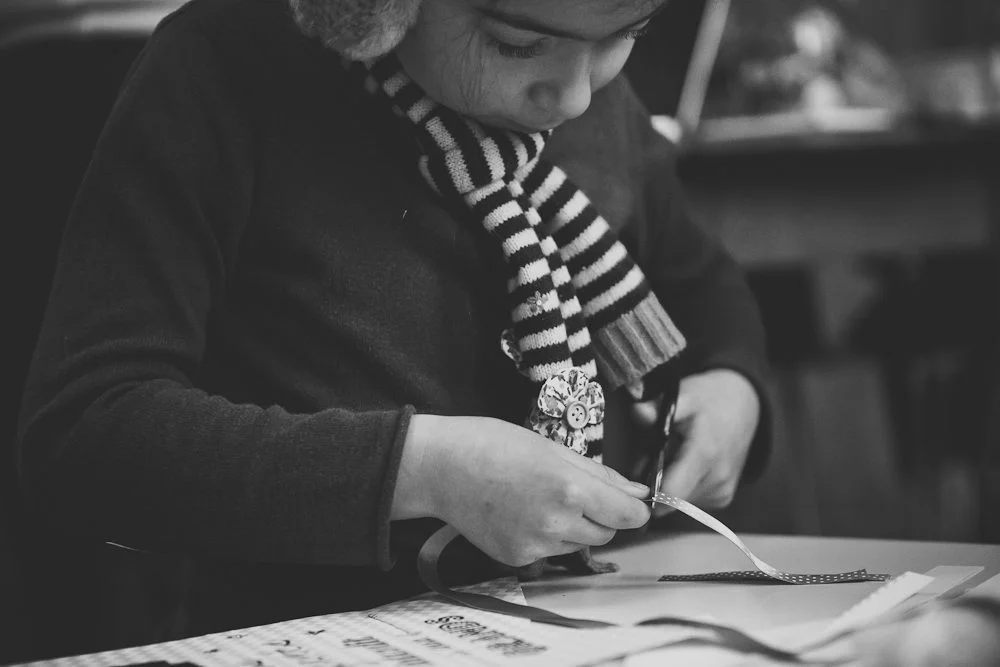 Enfant concentré créant une bannière DIY, photographie en noir et blanc à l'ambiance douce et artisanale.