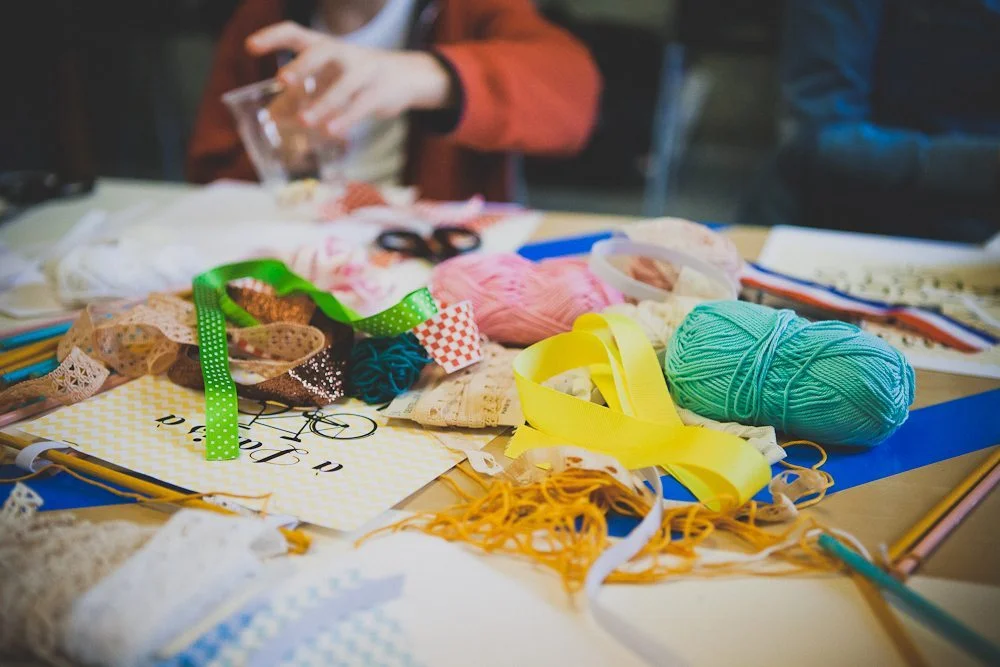 Matériel de couture coloré, rubans et fils disposés sur une table pour un atelier DIY créatif.