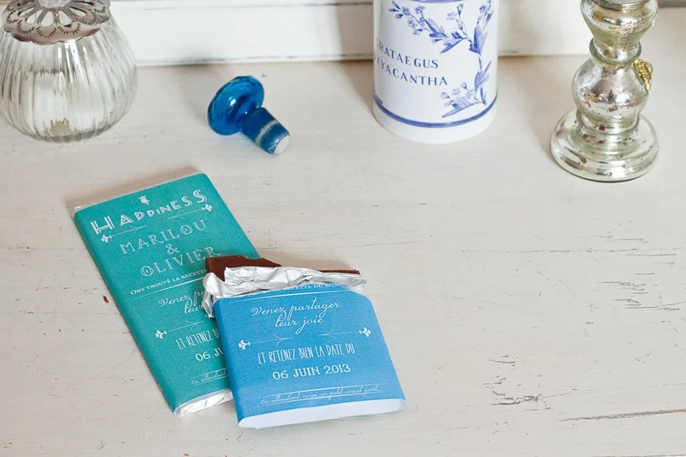 Deux tablettes de chocolat bleues personnalisées pour un Save the Date, posées sur une table blanche et lumineuse.