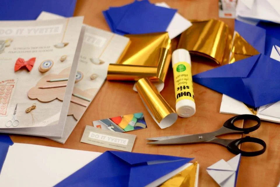 Fournitures de loisirs créatifs bleues et dorées, ciseaux et colle pour un atelier DIY de mariage.