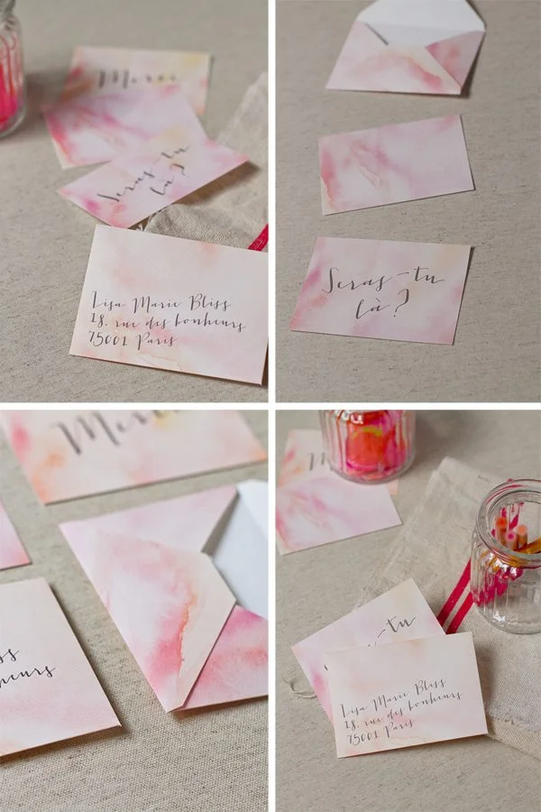 Enveloppes et cartes de mariage personnalisées avec des touches d'aquarelle rose et orange et une calligraphie élégante.