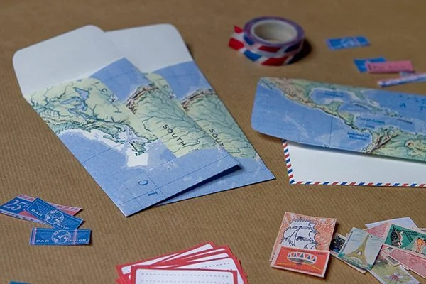 Matériel de papeterie bleu et blanc, timbres et enveloppes pour créer des invitations de mariage à thème voyage.
