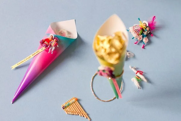 Cornets colorés en dégradé contenant des gourmandises et des figurines artisanales d'inspiration péruvienne.