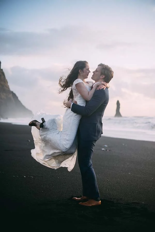 Un couple romantique sur une plage islandaise, célébrant leur amour après leur mariage.
