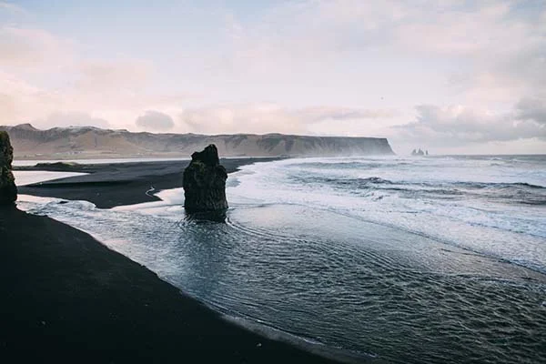 Magnifique scène de plage islandaise avec rochers érigés dans l'eau, idéal pour un shooting mariage Day After.