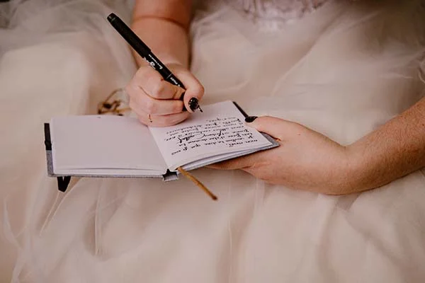 Un couple dans des vêtements de mariage écrit dans un journal intime, ambiante et romantique.