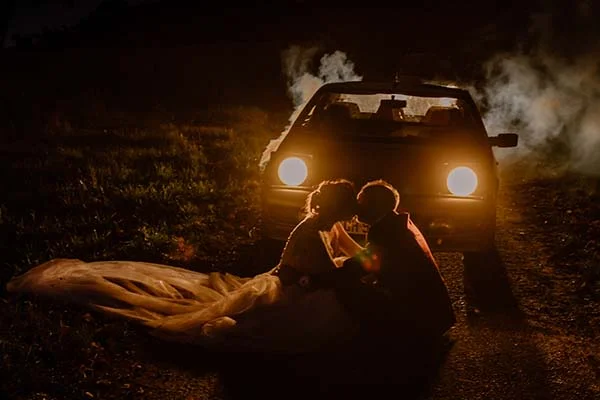 Un couple romantique partage un moment intime sous les feux lumineux d'une voiture convertible, inspirant des mariages