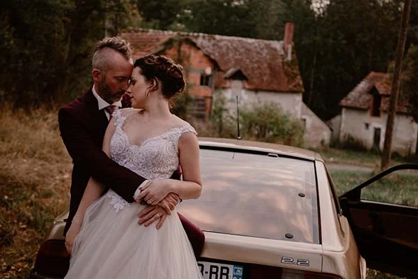 Un couple romantique à l'aise dans les bras l'un de l'autre, debout devant un modèle vintage, dans un décor paisible et charmant.