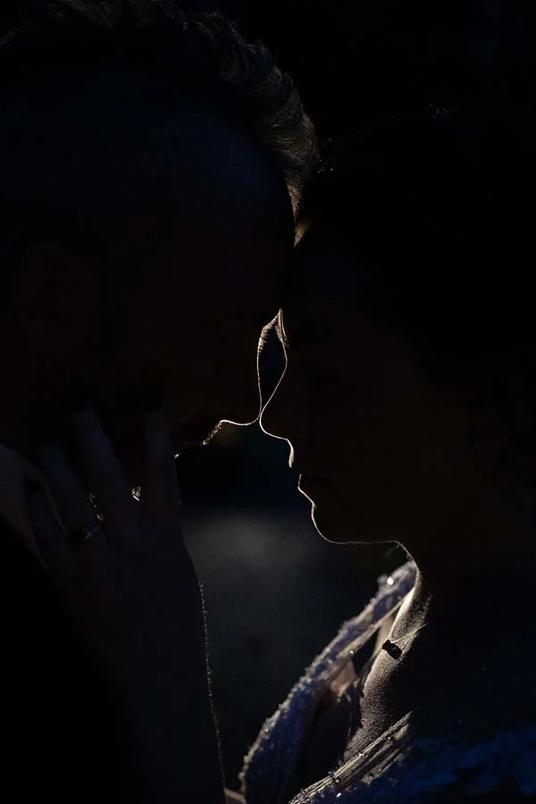 Un couple partage un moment intime dans la lumière du crépuscule, évoquant l'ambiance romantique d'un mariage à la mode.