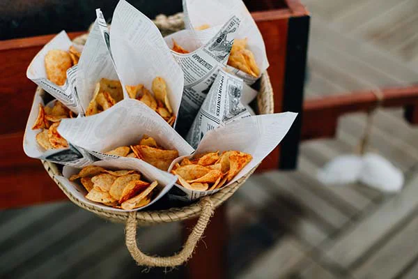 Cornets de chips artisanales dans un panier en osier pour un cocktail de mariage chic et bohème.