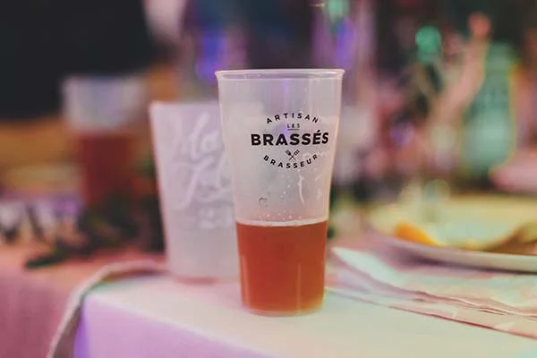 Un verre de bière artisanale sur une table de mariage, ambiance festive et chaleureuse aux tons pastels.