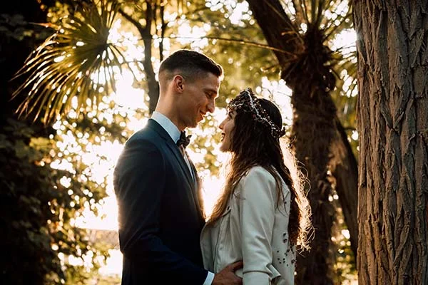 Couple marié s'enlaçant tendrement sous une lumière dorée dans un jardin luxuriant à Madrid.