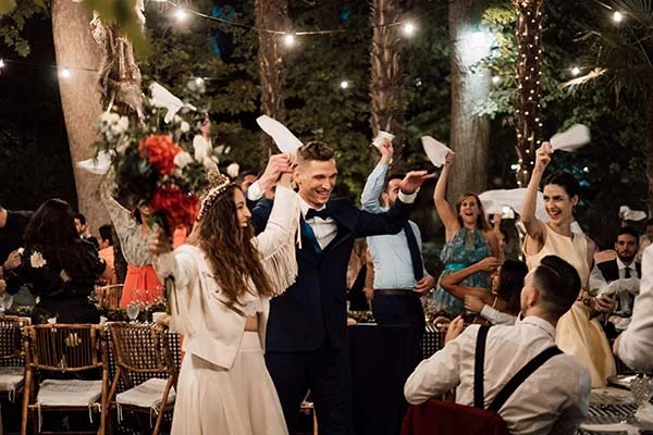 Jeunes mariés joyeux dansant sous des guirlandes lumineuses lors d'une soirée festive en extérieur à Madrid.