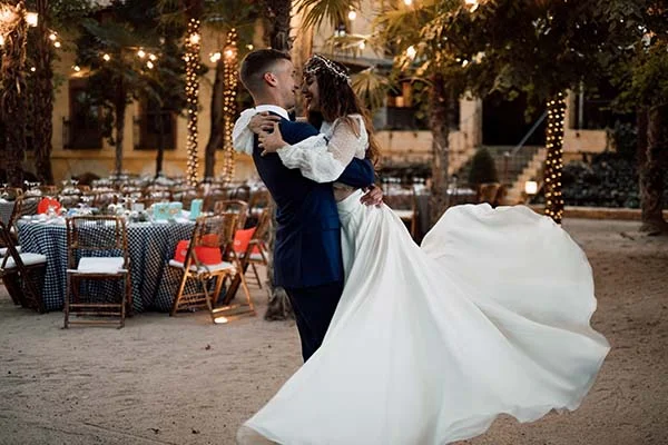 Jeunes mariés s'enlaçant et dansant avec joie lors d'une soirée bohème illuminée à Madrid.