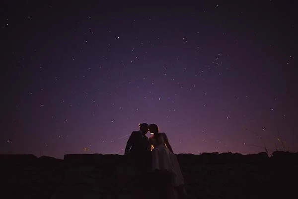 Silhouette d'un couple s'embrassant sous un ciel étoilé violet profond dans une ambiance romantique et nocturne.