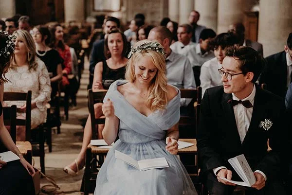 Une invitée en robe bleu clair et couronne de fleurs sourit lors du mariage d'Armony et Alexis.