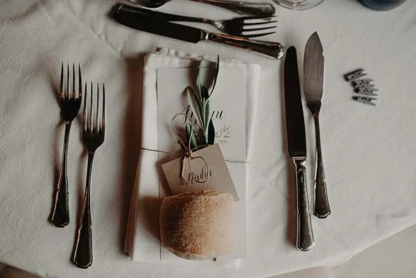 Dressage de table élégant avec couverts argentés, serviette blanche et marque-place personnalisé pour un mariage.