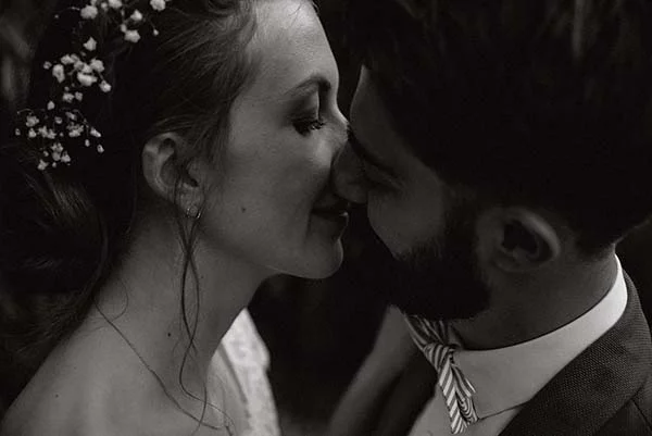 Gros plan en noir et blanc d'un couple de mariés s'apprêtant à s'embrasser dans une ambiance romantique.