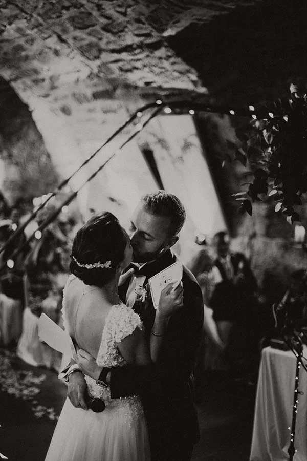 Couple de mariés s'embrassant tendrement lors d'une soirée chic, photographie en noir et blanc à l'ambiance romantique.