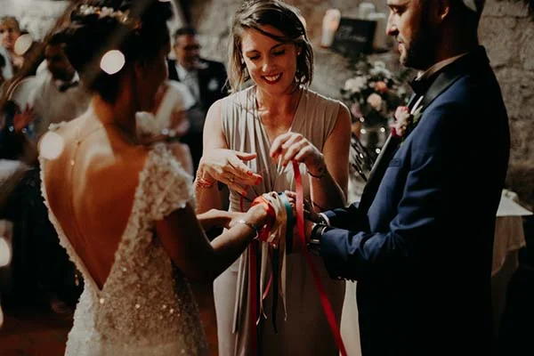 Une mariée et ses proches nouent des rubans colorés lors d'une réception élégante et chaleureuse.