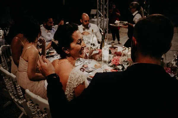 Une mariée rayonnante rit lors d'un dîner de mariage chic et élégant en soirée.