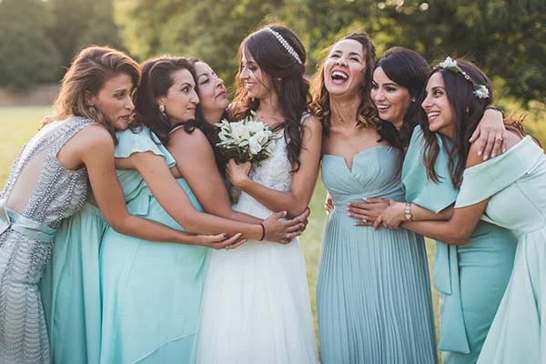 Une mariée rayonnante entourée de ses demoiselles d'honneur en robes bleu pastel lors d'un mariage champêtre.
