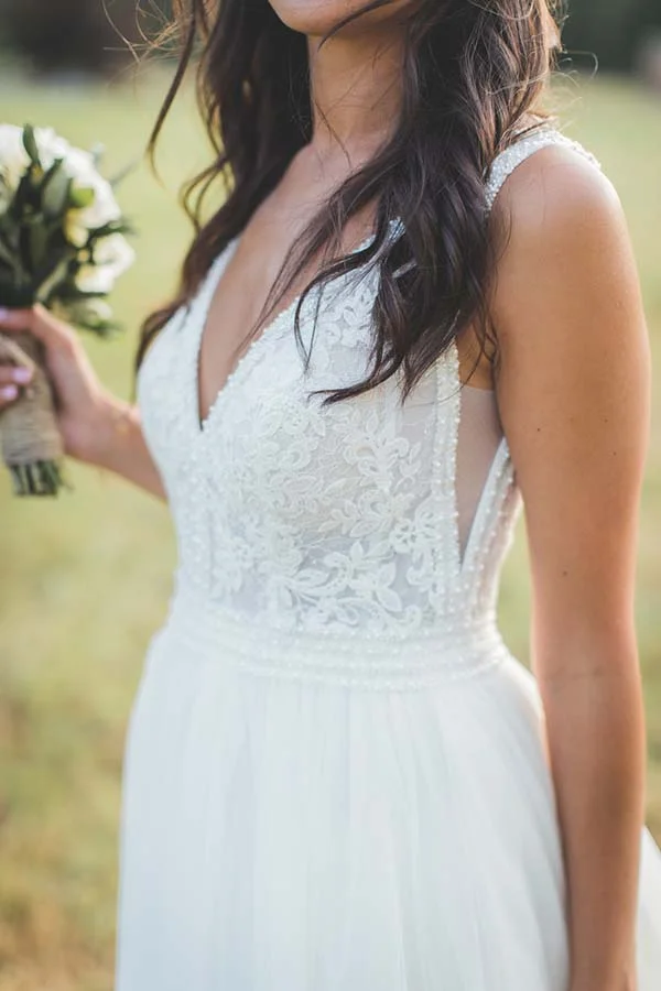 Mariée en robe blanche en dentelle tenant un bouquet champêtre, dans un cadre naturel et lumineux.
