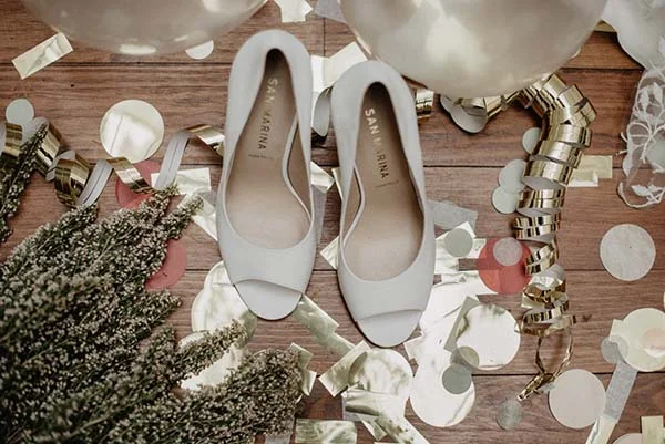 Élegantes sandales blanches pour le jour du mariage, entourées de décoration de fête et de ballons argentés.