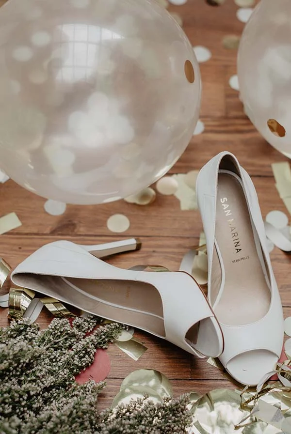 Chaussures blanches élégantes avec motifs de balles de cérémonie, idéales pour un mariage romantique et élégant.