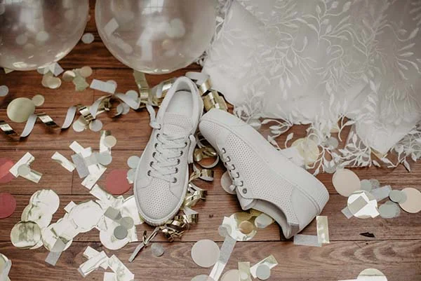 Élegance et célébration : chaussures blanches et confettis de mariage pour un look romantique.