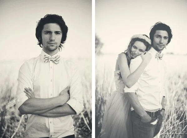 Un couple romantique dans des costumes de mari et mariée, capturé dans un instantané en noir et blanc dans un champ herbeux.
