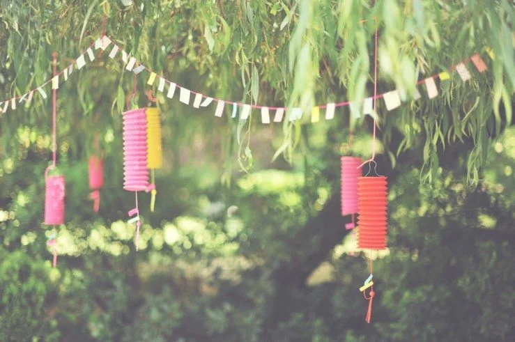 Un décor charmant avec des lampions colorés et des bandes de papier volant, idéal pour un mariage en plein air.