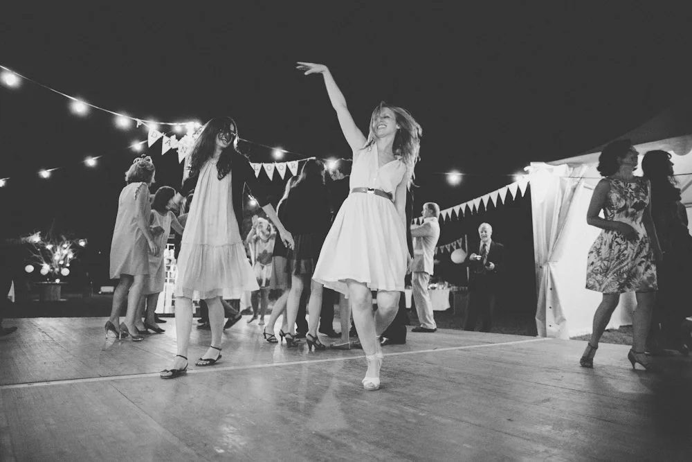 Une fête en plein cœur de la nuit, avec des femmes dans des robes blanches dansant sur une scène lumineuse.
