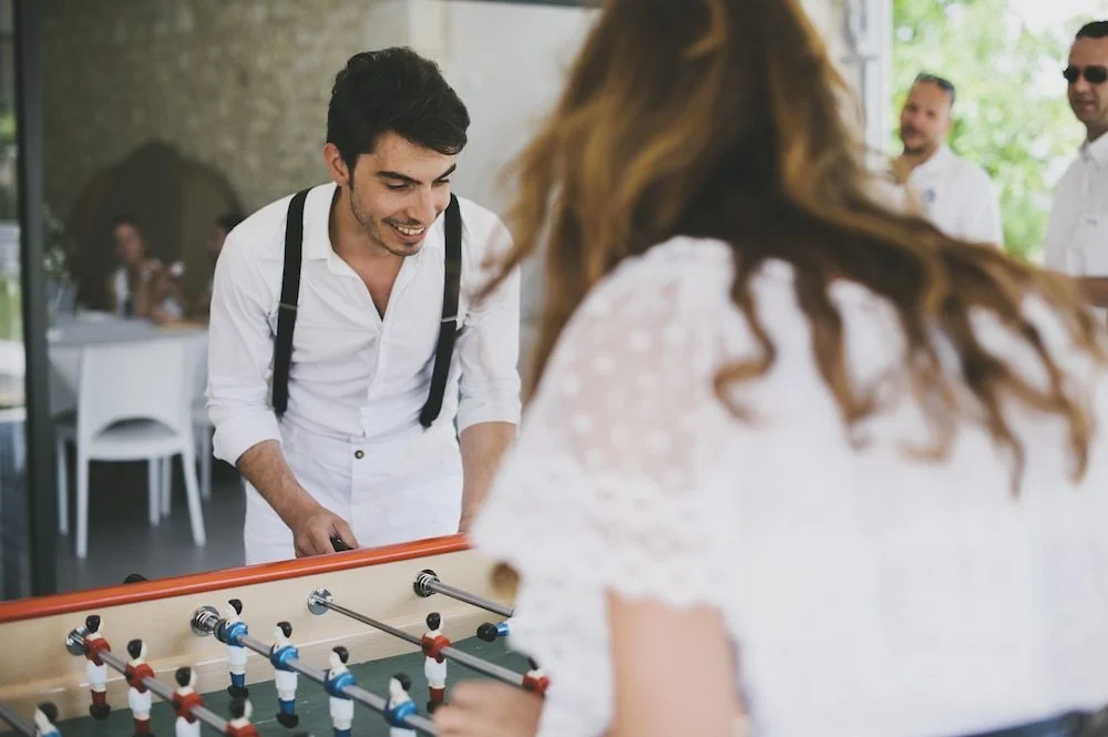 Un couple heureux joue au football, entouré de ses proches dans un décor de mariage rafraîchissant.