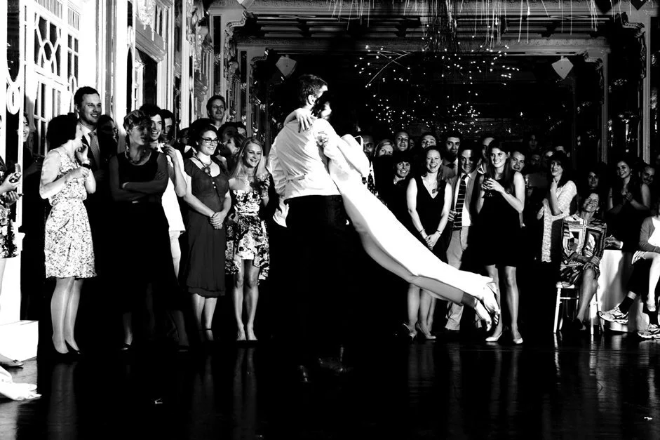 Un couple émotionnel dans une danse de début de mariage sous les yeux enthousiastes d'un public captivé.