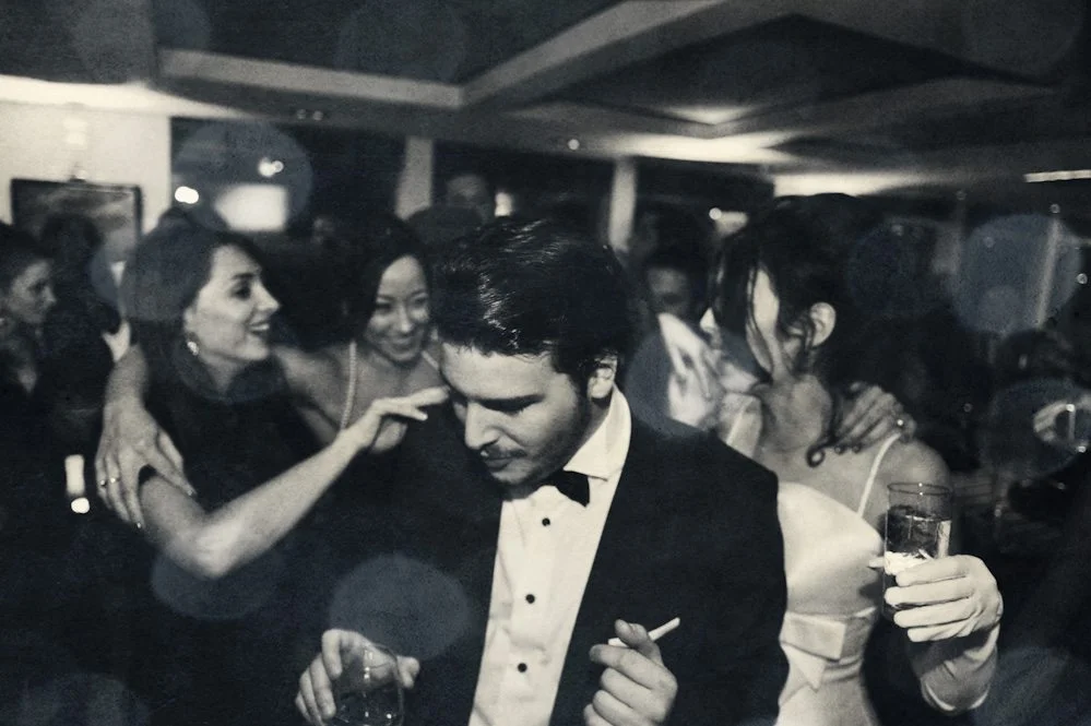 Une fête animée avec des invités élégants et riant, partageant des moments joyeux dans un décor de soirée sombre et chic.
