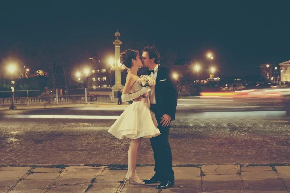 Un couple charmant dans des vêtements de mariage classiques partage un moment romantique sur une rue pavée de la nuit.