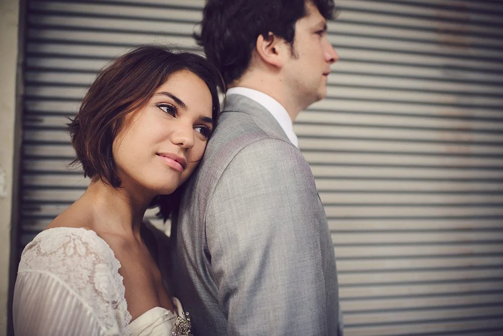 Mouvement romantique d'un couple de mariés contre un fond industriel, incarnant l'élégance et l'émotion du jour le plus spécial.