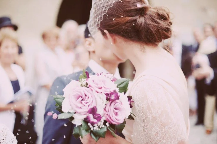 Un couple de mariée et de mari en larmes partageant un moment tendre au mariage, entouré de confetti en l'air.