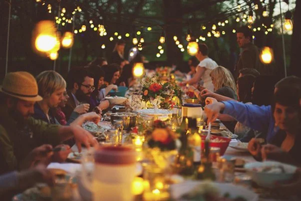 Un banquet intime et accueillant avec des luminaires chauds et des fleurs colorées, créant un ambiance chaleureuse et conviviale.